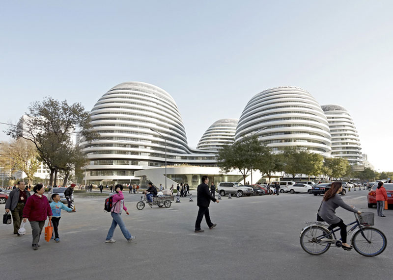 Exterior view during the day of the Galaxy SOHO Complex in Beijing designed by Zaha Hadid with civilians on the ground