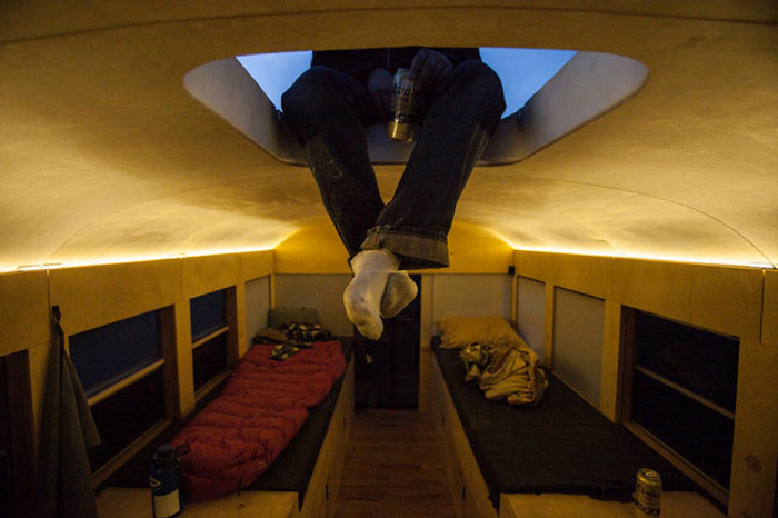 Man sitting on the sunroof of a converted school bus