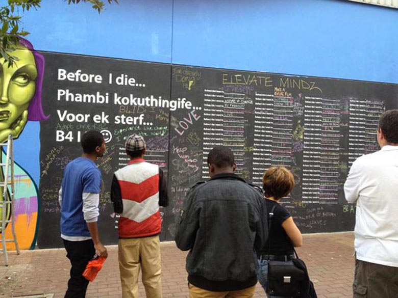 2 women writing on the Before I Die wall by Candy Chang in Johannesburg South Africa