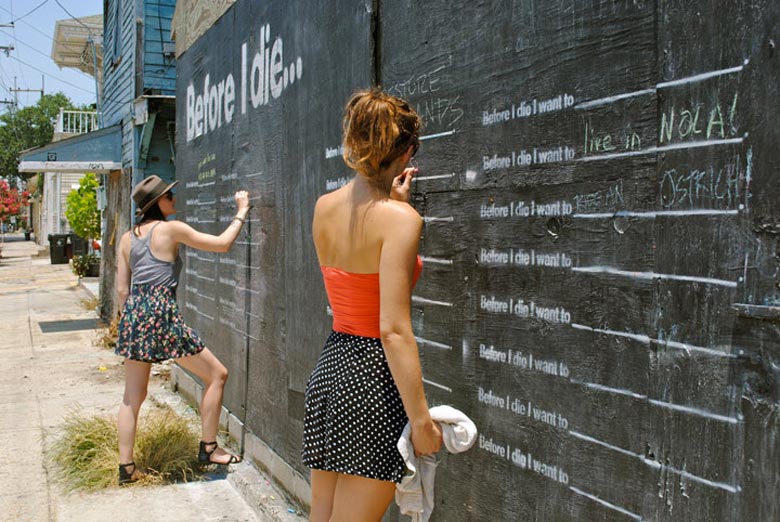 2 women writing on the Before I Die wall by Candy Chang