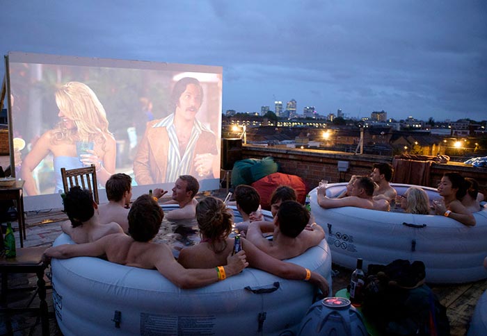 People watching a movie in Hot Tubs at the Rooftop Cinema at Rockwell House in London