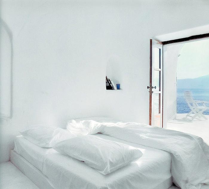 Bedroom with white walls and beddings at Perivolas Hideaway in Thirassia, Santorini