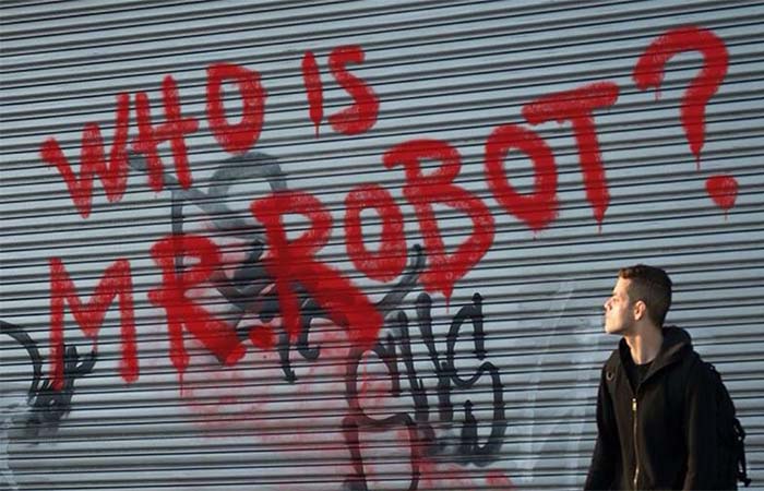 Elliot Alderson next to Who Is Mr Robot graffiti 