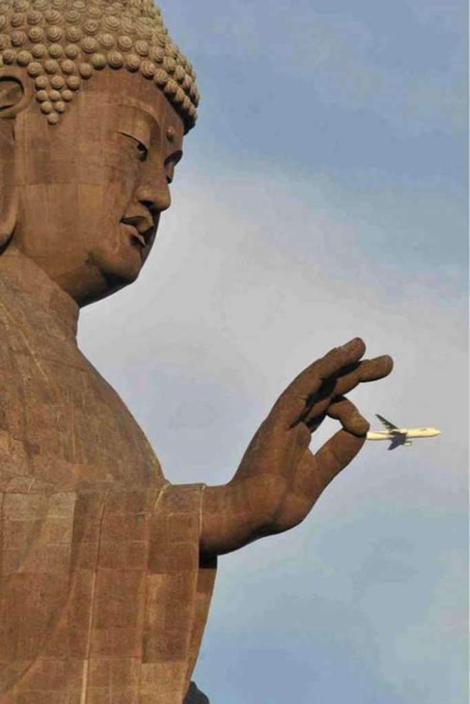 A plane flying next to a monument's hand