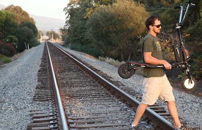 A guy carrying Freedom Electric Stand Up Trikke