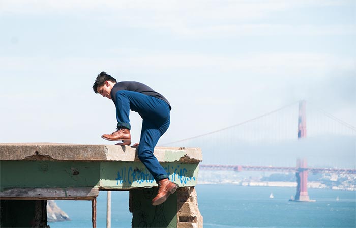 A guy climbing a concrete wall wearing The Venture Pant