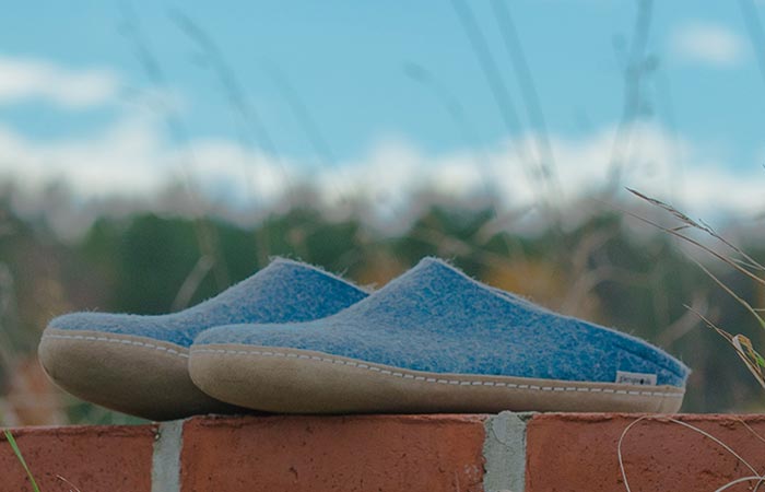Glerups slip ons, blue, outdoor, on a brick wall.