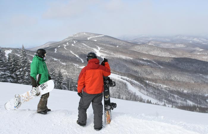 Two snowboarders in Killington ski resort, observing the mountain and runs.