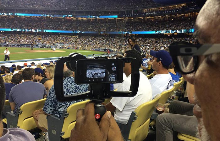 A man filming the NFL game captured from behind. 