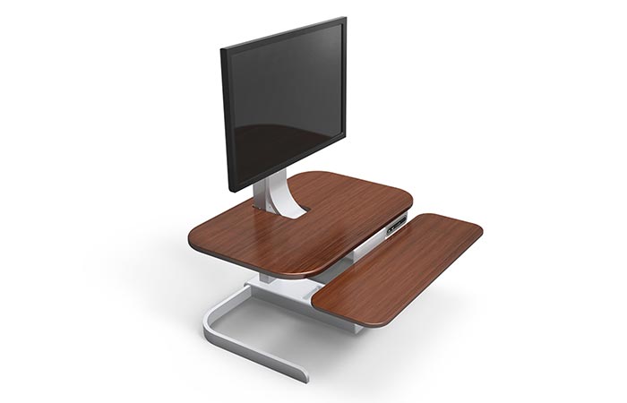 Crossover Motorized Standing Desk , brown with aluminum frame, tilted, with a computer monitor on top, on a white background.