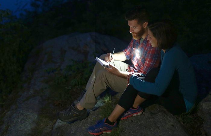 A man and a woman reading something in the dark and using the gadget. 