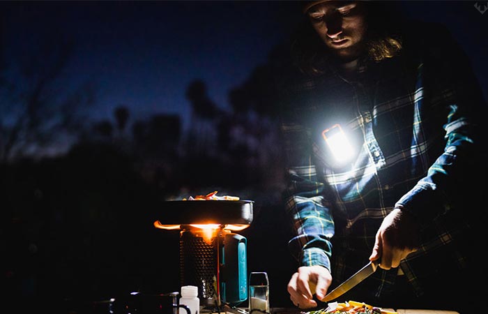 A guy camping and using the gadget during the night. 