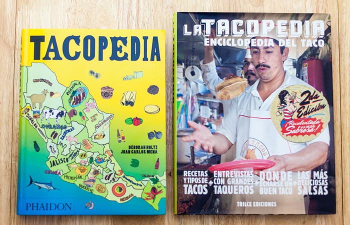 Tacopedia, adapted English version and original Mexican edition, on a wooden surface.