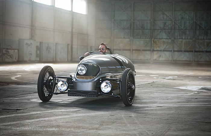 A Guy Driving Morgan EV3 Electric Car In The Empty Hall