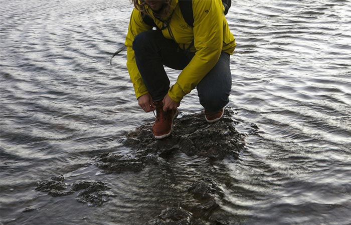 Man tying his shoe laces while standing in water