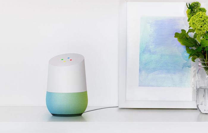 Google Home On A White Table Next To A Painting