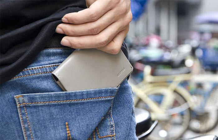 Man placing the grey Ikepod wallet into his pocket