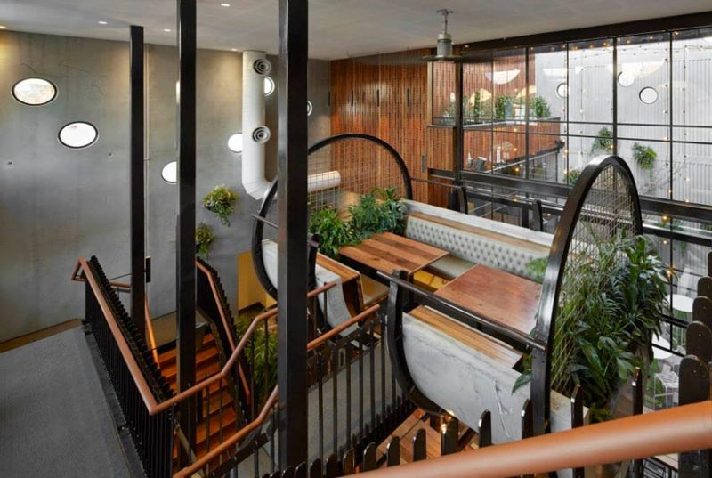 seating booth surrounded by green plants and stairs to the first floor at the Prahran Hotel