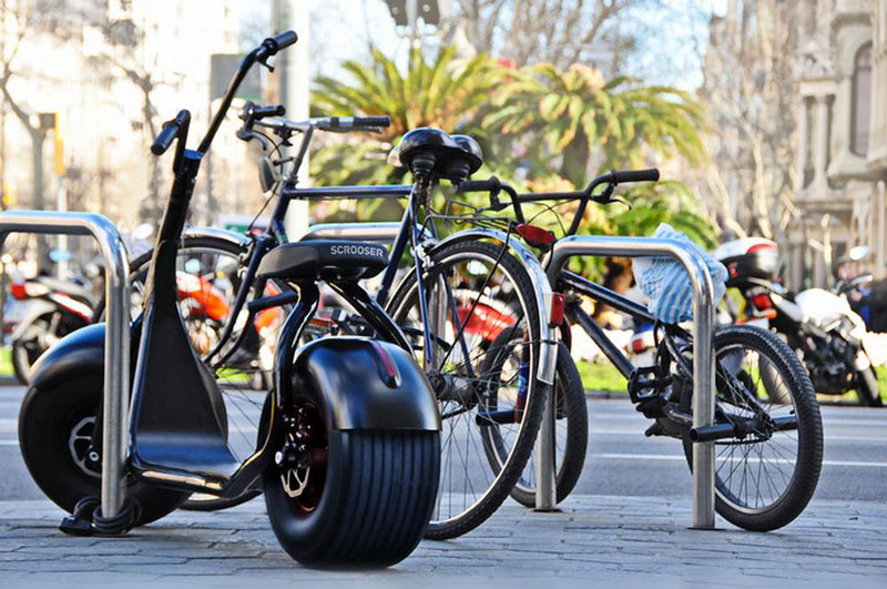 Black Scrooser motionless near other bicyles