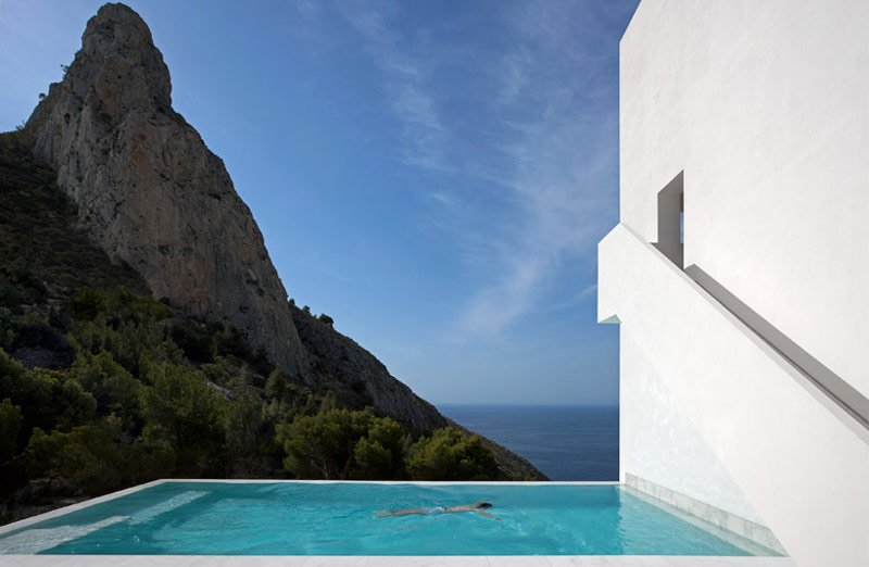 Woman swimming in a pool overlooking the scenery of an ocean at the House on the Cliff by Fran Silvestre Arquitectos