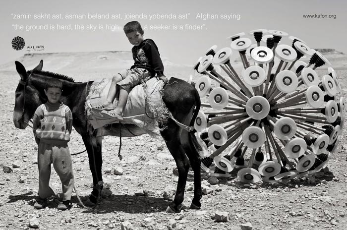 2 boys and a donkey in the desert pulling a Mine Kafon Minefield Sweeper
