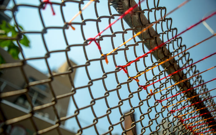 Yarn tied to a fence at the Williamsburg Bridge, a project from HOT TEA
