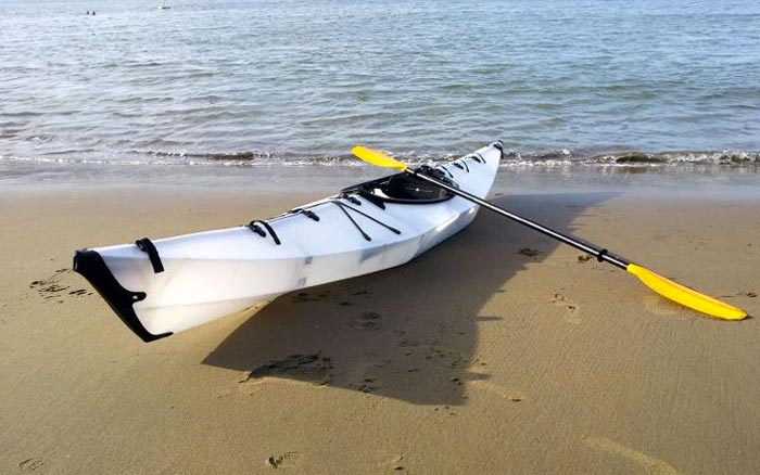 Oru Kayak on a beach with a paddle