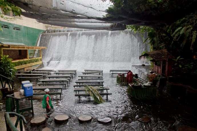 View of the waterfall and tables at the Villa Escudero Resort Waterfall Restaurant in the Philippines
