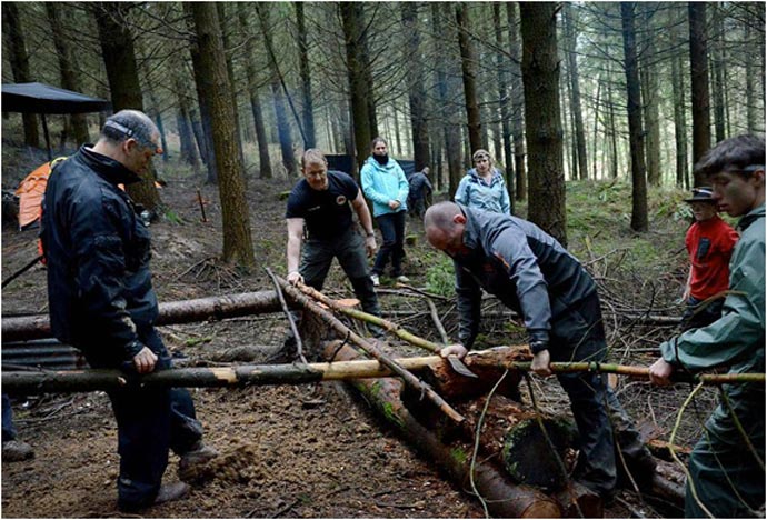 Men working with wood in the forest during the Bear Grylls Survival Academy
