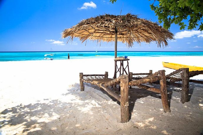 Sandy beach and lounge chair with umbrella at Manta Resort