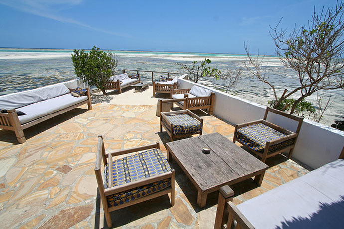 Terrace with wooden tables and chairs at The Rock Restaurant in Zanzibar