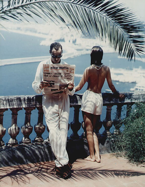 Guy reads newspaper and lady looks at the seaside, terrace view