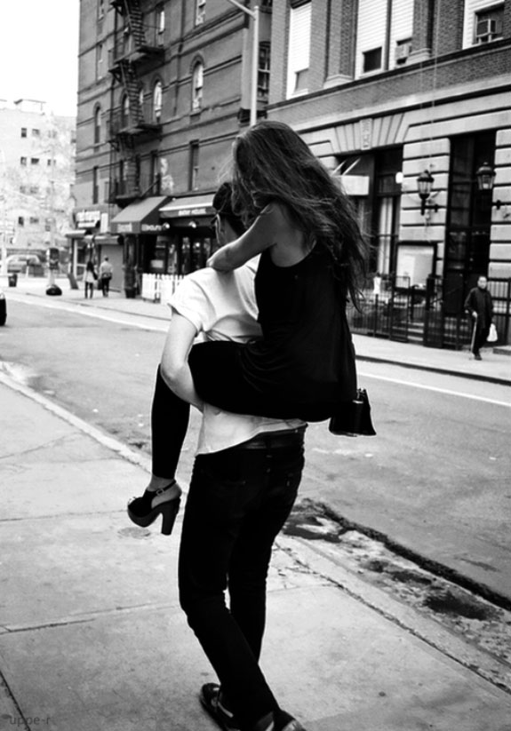 Black and white photo, guy carries a girl in a black dress