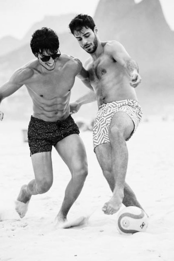 Black and white beach photo of two guys playing football on sand beach