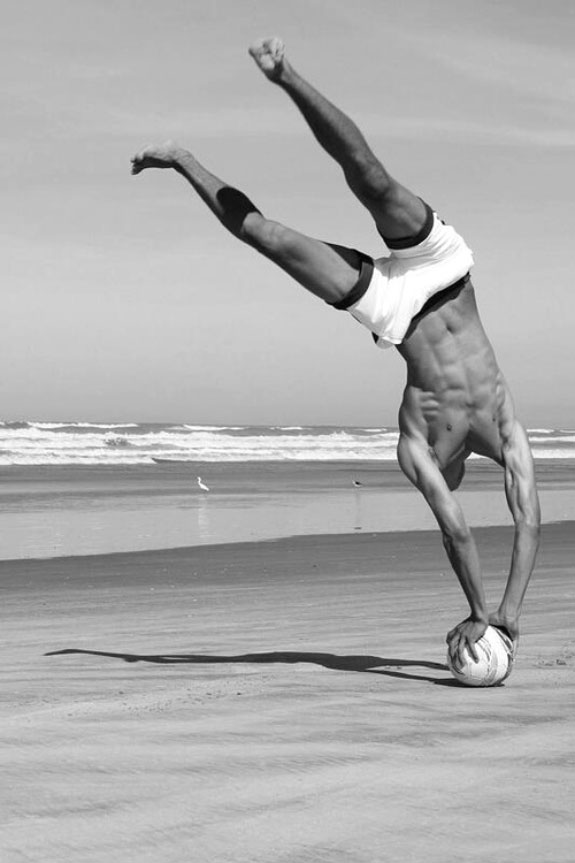 Black and white photo, guy on beach standing in a ball with his hands