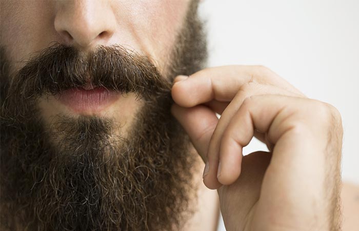 A guy with the beard holding his moustaches 