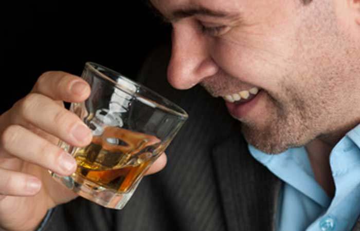 A man smiling while drinking whiskey