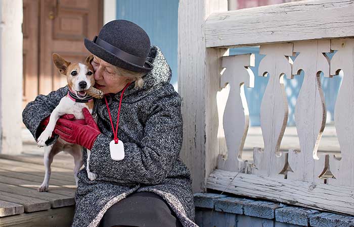 Older lady sitting on a porch with a dog wearing GPS location device