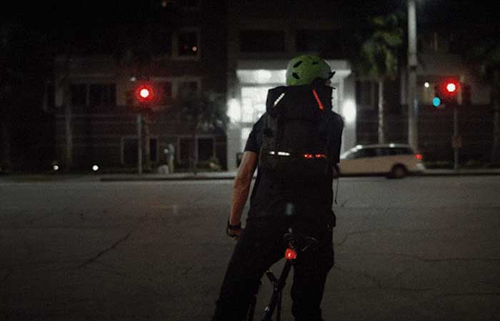 LED Illuminated and App Controled Active Apparel by Lumenus on a biker's backpack