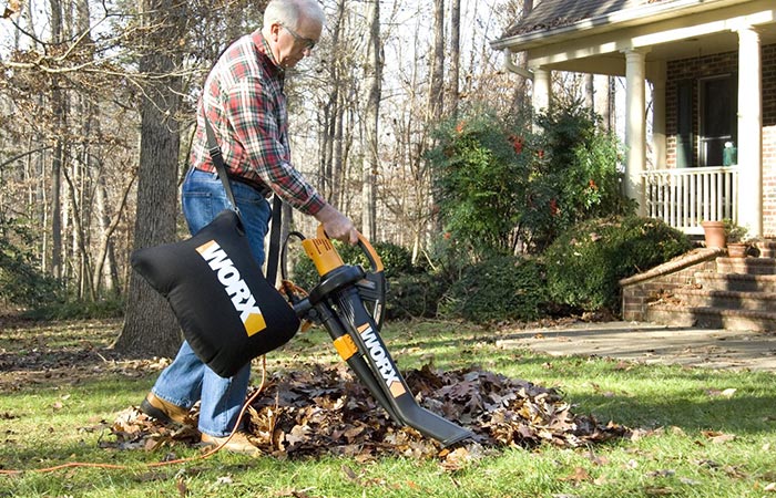Older man cleaning leaves with WORX WG509 Electric TriVac BlowerMulcherVacuum