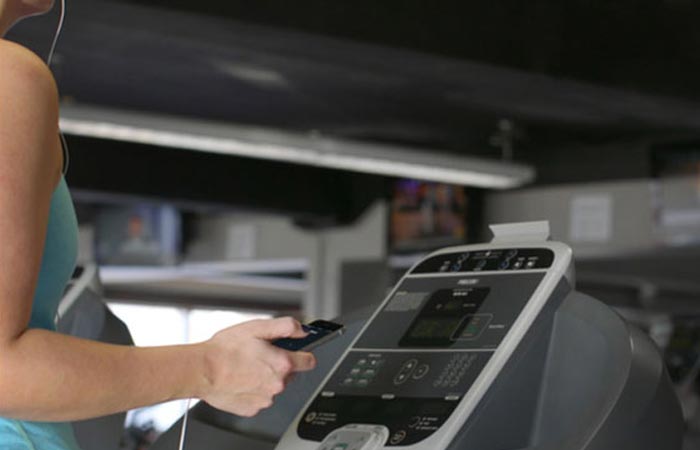 A woman running on a treadmill at the gym, using blipcast technology.