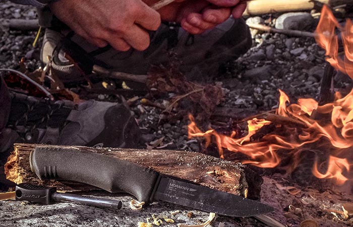A knife placed on a rock in the wild by the fire. 