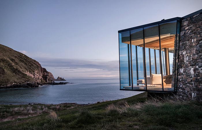 Seascape Retreat on a South Pacific Cove, a view at the glass terrace and the bay from the outside, at sundown.
