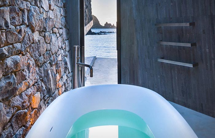 Seascape Retreat on a South Pacific Cove indoor bathtub, filled with wate, with a view on the bay though the open door.