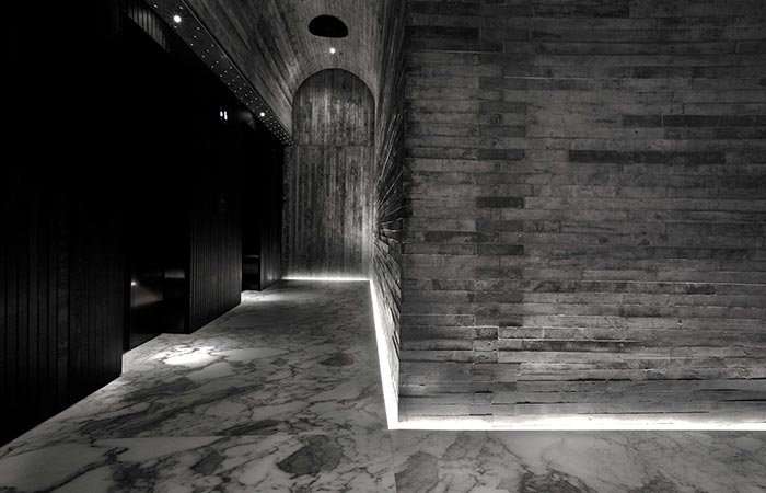 TUVE Boutique Hotel hallway with marble floor and black and grey textured walls.