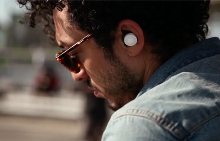 A man in the street with white Doppler Labs Here Active Listening Earbuds.