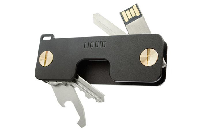 Key Caddy, black, with keys, a bottle opener and USB spread around, on a white background.