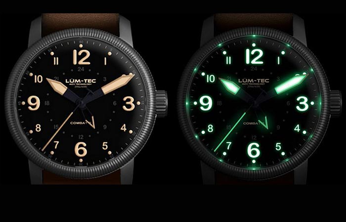 Lum Tec Combat B33 GMT watch with white display and with old radium tone luminescence display, on a black background.