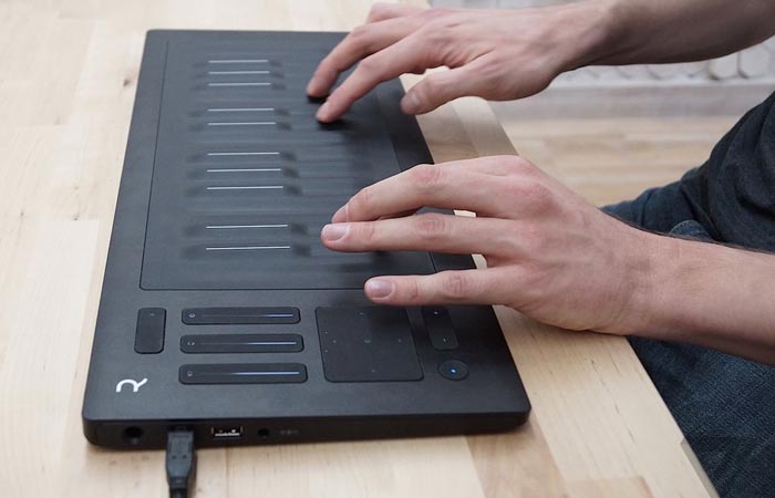 Roli Seaboard Rise laid on a wooden table, played with two hands.