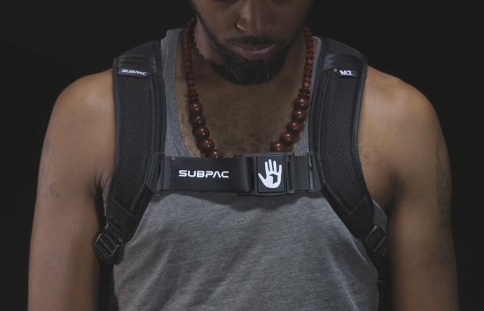 SubPac M2 worn by a man in a grey shirt, front view, with a black background.